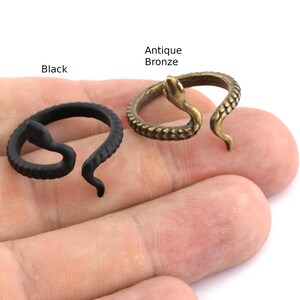 Op de afbeelding: Twee slangenringen, één zwart en één antiek brons. De zwarte ring is mat, terwijl de bronzen ring een getextureerde, verouderde uitstraling heeft. De ringen worden op een lichte achtergrond weergegeven, met de woorden "Black" en "Antique Bronze" boven elke ring.