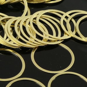 May include: A pile of gold-colored metal rings, some stacked on top of each other, on a black background.