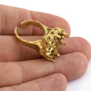 Op de afbeelding: Een ringsetting van goudkleurig metaal met een decoratief opengewerkt ontwerp. De ring is ontworpen om een grote steen of cabochon te bevatten.