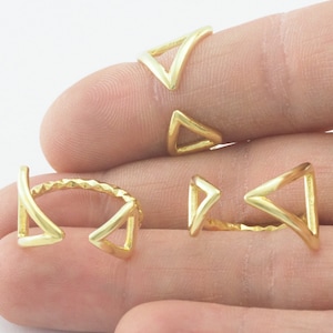 May include: Four gold-toned triangle shaped rings. The rings are open and adjustable. The rings are on a hand.