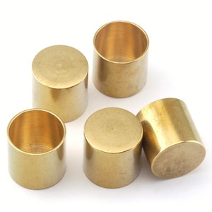 Puede incluir: Cinco tapas de cilindro de metal de color dorado, posiblemente para muebles o fines decorativos.