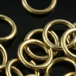Op de afbeelding: Een close-up van een stapel gouden springringen. De ringen zijn allemaal even groot en zijn in een willekeurig patroon gerangschikt.