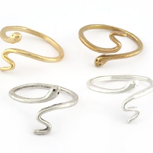 May include: Four snake-shaped rings, two gold and two silver. The rings are simple and elegant, with a subtle snake design.