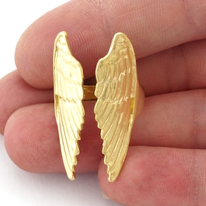 May include: Gold-toned ring with a design of two angel wings.