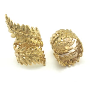 Puede incluir: Dos anillos de oro con un diseño de hoja de helecho. Los anillos están hechos de metal y tienen un diseño detallado e intrincado.