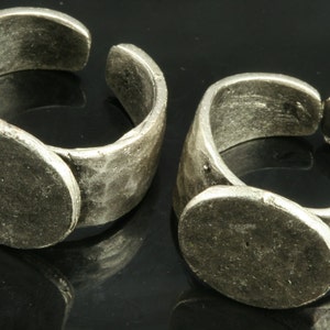 K&ouml;nnte beinhalten: Zwei silberne Ringe mit einer runden, flachen, leeren Oberfl&auml;che auf der Oberseite. Die Ringe sind verstellbar und haben eine rustikale, geh&auml;mmerte Oberfl&auml;che.