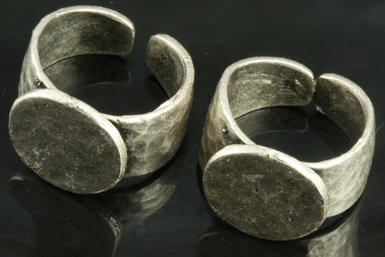 K&ouml;nnte beinhalten: Zwei silberne Ringe mit einer runden, flachen, leeren Oberfl&auml;che auf der Oberseite. Die Ringe sind verstellbar und haben eine rustikale, geh&auml;mmerte Oberfl&auml;che.