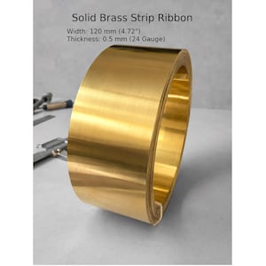 May include: A roll of solid brass strip ribbon. The width is 4.72 inches, and the thickness is 0.5 mm (24 gauge). The ribbon has a shiny, golden color and is tightly coiled.