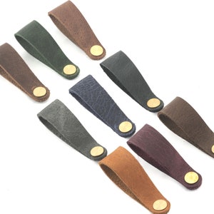 Può includere: Nove cinturini in pelle con fibbie in ottone in vari colori, tra cui marrone, verde, grigio, blu, viola e beige.