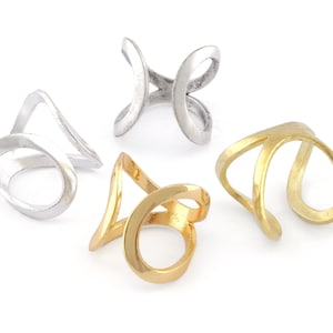 May include: Four metal rings in two different styles. Two rings are silver and two are gold. The rings are open and have a curved design.