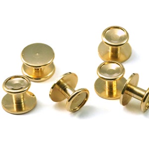 May include: Six gold-toned metal button snaps with a round top and a small post. The snaps are arranged in a semi-circle on a white surface.