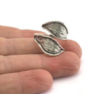 A silver ring with a leaf design. The ring is open and adjustable.