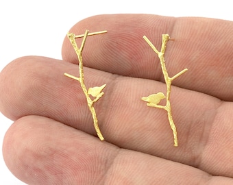 May include: A pair of gold-tone earrings featuring a delicate branch design with a small bird perched on each branch.