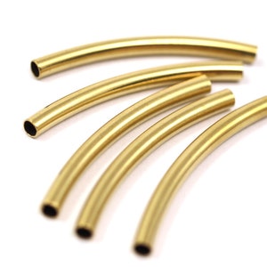 May include: Five gold-colored metal tubes, each bent into a gentle arc, are arranged in a fan shape. The tubes are smooth and shiny, with a slightly rounded edge.