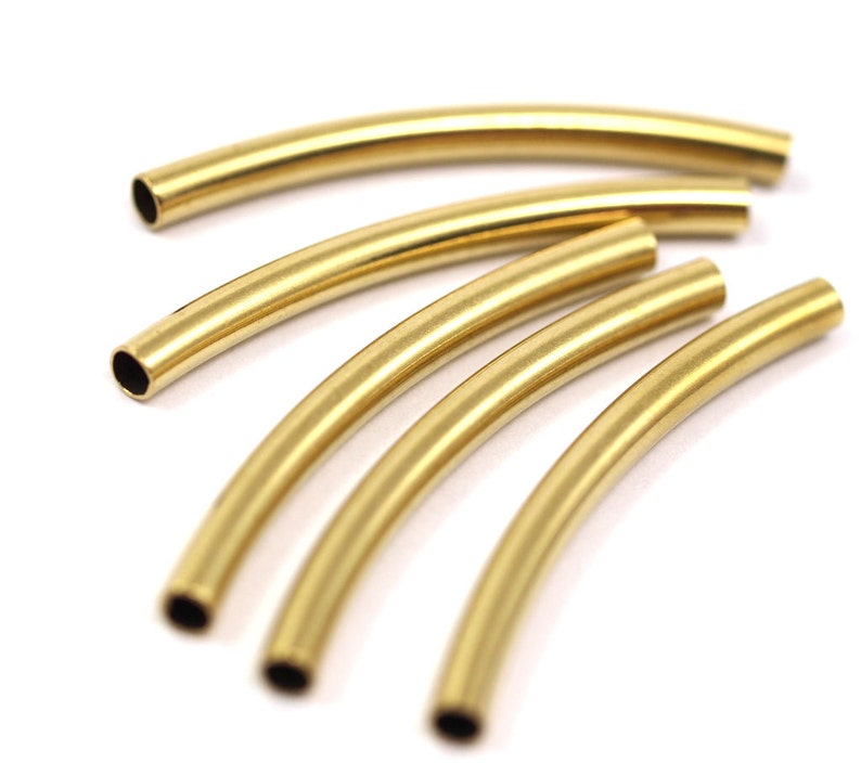 May include: Five gold-colored metal tubes, each bent into a gentle arc, are arranged in a fan shape. The tubes are smooth and shiny, with a slightly rounded edge.
