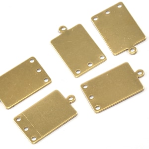May include: Five gold-toned metal rectangular tags with rounded corners and holes for attaching to a necklace or bracelet. Each tag has four holes for attaching jump rings or other jewelry findings.