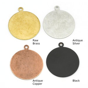May include: Four round metal blanks with a hole at the top for hanging. The blanks are in four different finishes: raw brass, antique silver, antique copper, and black.