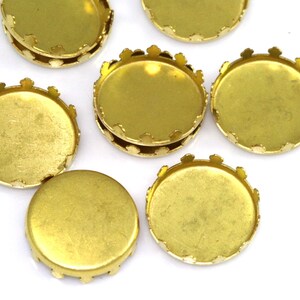 Op de afbeelding: Een set gouden metalen bezel-instellingen met gegolfde randen. De bezels zijn rond en hebben een gladde, glanzende afwerking.