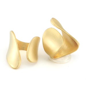 May include: Two gold-toned open rings with a smooth, matte finish. The rings are made of metal and have a simple, modern design.