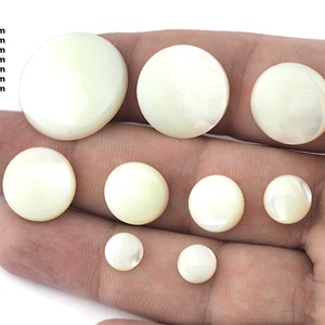 Puede incluir: Surtido de cabujones de madreperla blanca de 8 a 25 mm. Los cabujones son redondos y lisos, con un ligero brillo iridiscente.