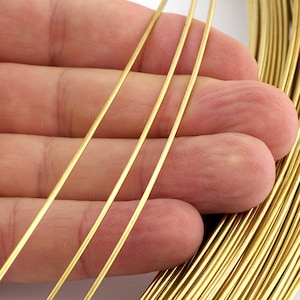 Può includere: Primo piano di diversi fili di filo color oro, con un fascio di filo sullo sfondo. Il filo è sottile e sembra essere fatto di metallo, probabilmente per la creazione di gioielli o artigianato.