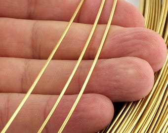 Pode incluir: Close-up de vários fios de arame dourado, com um feixe de arame ao fundo. O arame é fino e parece ser feito de metal, provavelmente para fazer joias ou artesanato.