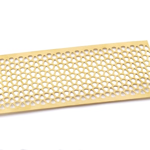 May include: A gold metal mesh tray with a geometric pattern. The tray is rectangular and has a smooth surface.