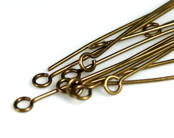 May include: A close-up of a pile of gold-colored metal head pins with eye loops. The head pins are used for jewelry making and crafting.