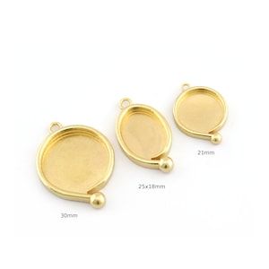 May include: Three gold-coloured metal bezel trays in different sizes. The largest is 30mm, the middle is 25x18mm, and the smallest is 21mm. Each has a loop for hanging and a decorative ball on the side.