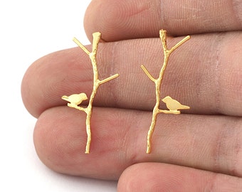 May include: A pair of gold-tone earrings featuring a delicate silhouette of a bird perched on a branch.