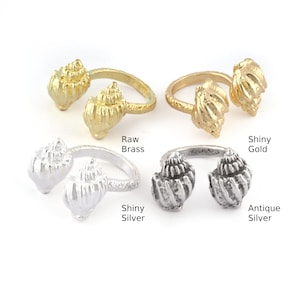 May include: Four adjustable rings featuring a seashell design. The rings are displayed in four different finishes: raw brass, shiny gold, shiny silver, and antique silver.