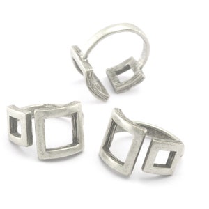 May include: Three silver rings with a square design. The rings are open and have a curved shape.