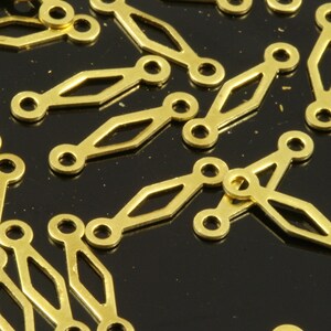 Op de afbeelding: Een close-up van een groep gouden metalen connectoren. De connectoren zijn gevormd als een reeks verbonden ovalen met een diamantvormige uitsparing in het midden.