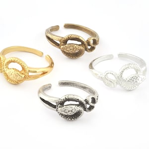 Könnte beinhalten: Vier verstellbare Schlangenringe in Gold, Silber und Bronze. Jeder Ring zeigt ein detailliertes Schlangendesign mit einer strukturierten Oberfläche.