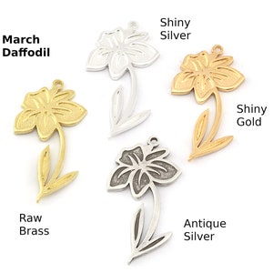 May include: Four metal daffodil charms in different finishes: raw brass, antique silver, shiny silver, and shiny gold.  March Daffodil is written above the raw brass charm.