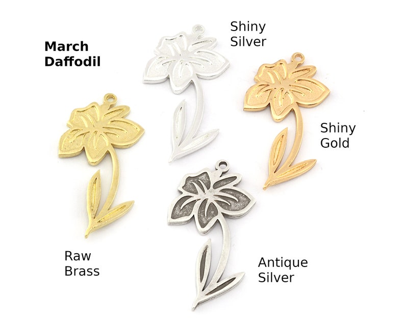 May include: Four metal daffodil charms in different finishes: raw brass, antique silver, shiny silver, and shiny gold.  March Daffodil is written above the raw brass charm.