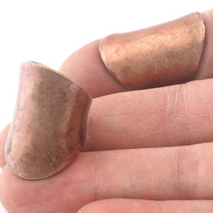 May include: Two copper rings, one on top of the other, on a finger. The rings are smooth and have a slightly rounded shape.