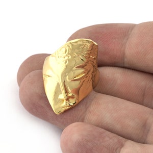Peut inclure: Une bague en or avec un motif de visage abstrait textur&eacute;.