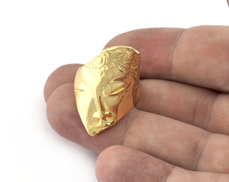 Peut inclure: Une bague en or avec un motif de visage abstrait textur&eacute;.