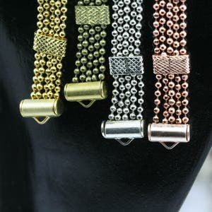 May include: Four strands of chain with different colored metal clasps. The chains are gold, brass, silver, and rose gold.