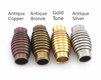 May include: Four metal magnetic clasps in antique copper, antique bronze, gold tone, and antique silver. Each clasp is barrel-shaped with horizontal ridges. Text above each clasp indicates the color.