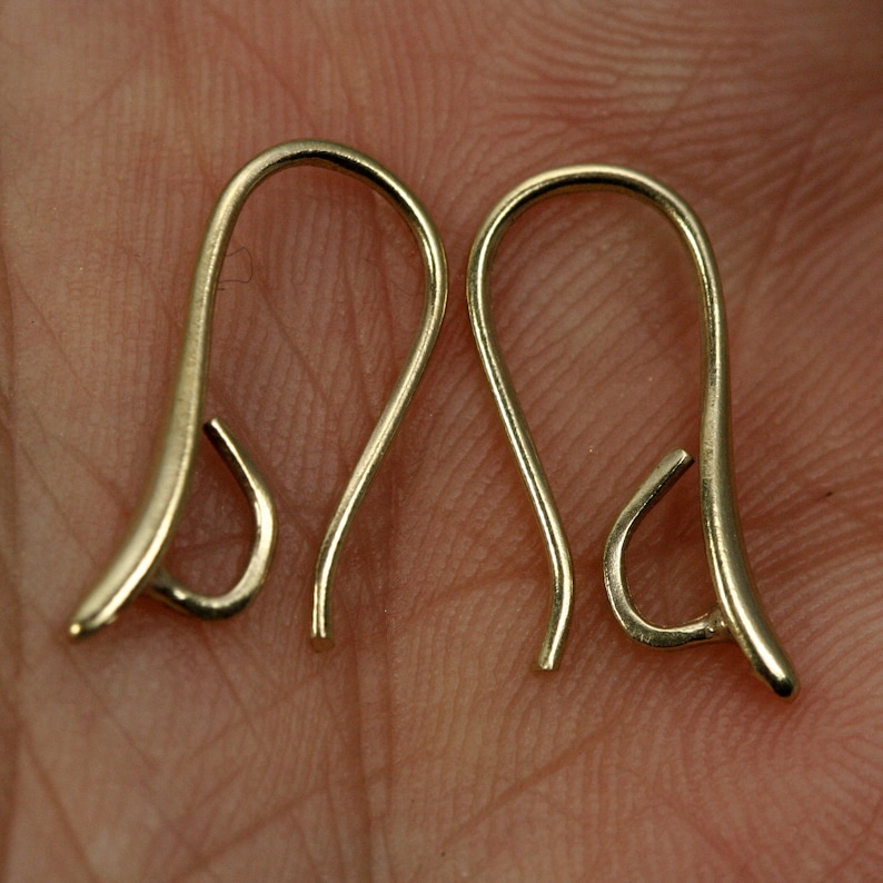 May include: Two gold-toned earring hooks, each with a curved wire and a small loop at the end.