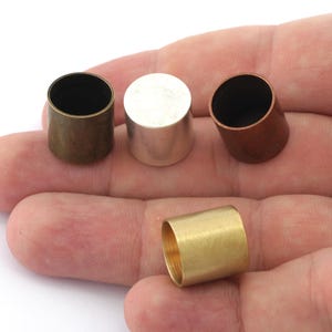 Puede incluir: Cuatro tapas met&aacute;licas de diferentes colores: lat&oacute;n, plata, cobre y oro. Las tapas son cil&iacute;ndricas y tienen un acabado liso.