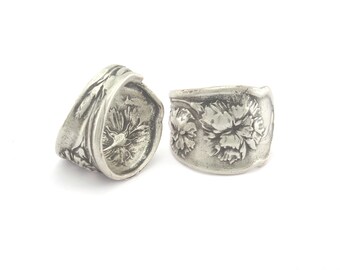May include: Two silver rings with floral designs. The rings are made from recycled silverware and feature a delicate floral pattern.