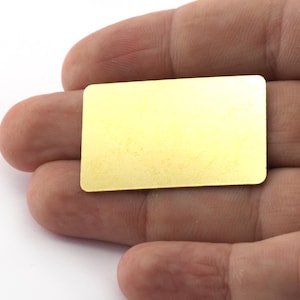 Può includere: Un piccolo foglio di metallo rettangolare di colore dorato.