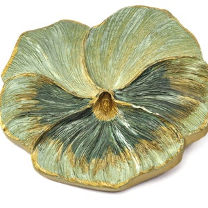 May include: A green and gold decorative dish shaped like a pansy flower. The dish has a textured surface and a raised center.
