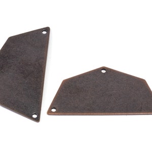 May include: Two antique copper-toned metal shapes with rounded edges and holes. The shapes are similar in size and style, with one being slightly larger than the other.