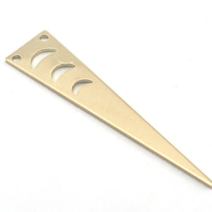 Pode incluir: Pingente triangular de metal dourado com um design de lua crescente recortado.