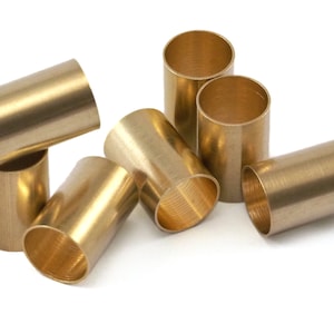 May include: A group of six brass tubes of varying sizes, arranged in a cluster on a white background. The tubes are smooth and shiny, with a slightly textured surface.
