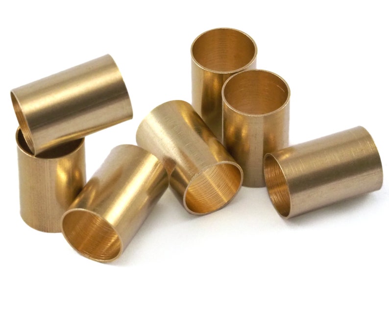 May include: A group of six brass tubes of varying sizes, arranged in a cluster on a white background. The tubes are smooth and shiny, with a slightly textured surface.